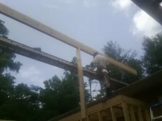 Carpenter setting a ridge beam over a new addition frame — Ice Dam Removal by Roofing Brothers in Pflugerville