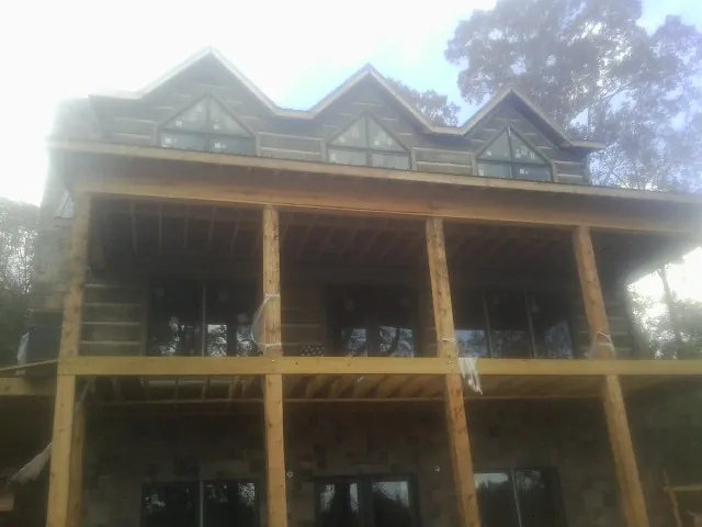 Dormers and porch framing on a large log home under construction — Roof Coating work by our crew in Pflugerville