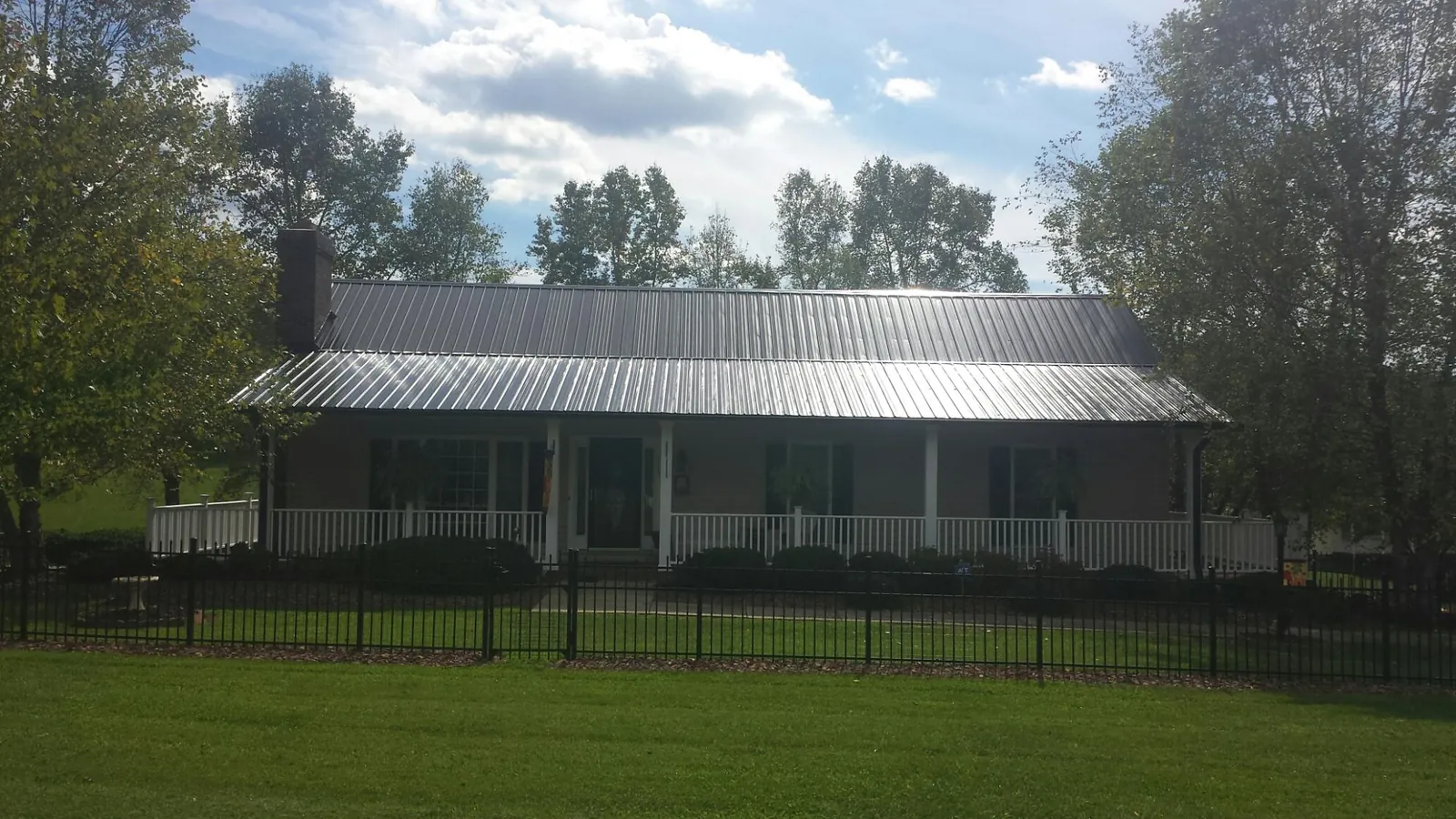 Gray metal roof on a brick ranch with a full width front porch — Gutter Guard Installation work by our crew in Pflugerville